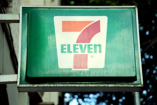 A close-up of a 7-Eleven store sign in a city environment, outdoors. Franchise advertising case studies, compared against a simple transfer test