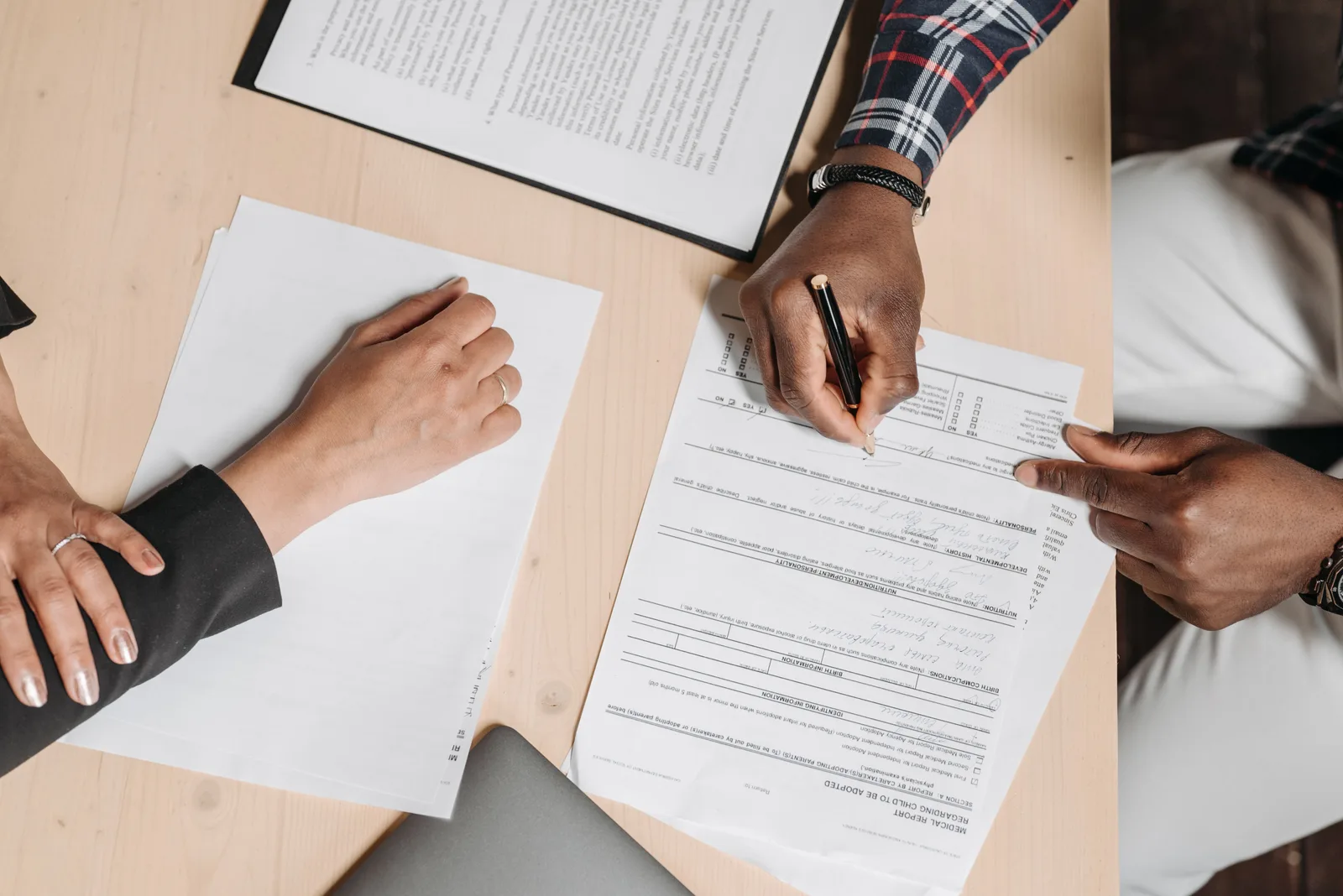 Close-up of two people signing documents at an office desk, depicting business collaboration. Franchise brand management trends: AI search, human sign-off