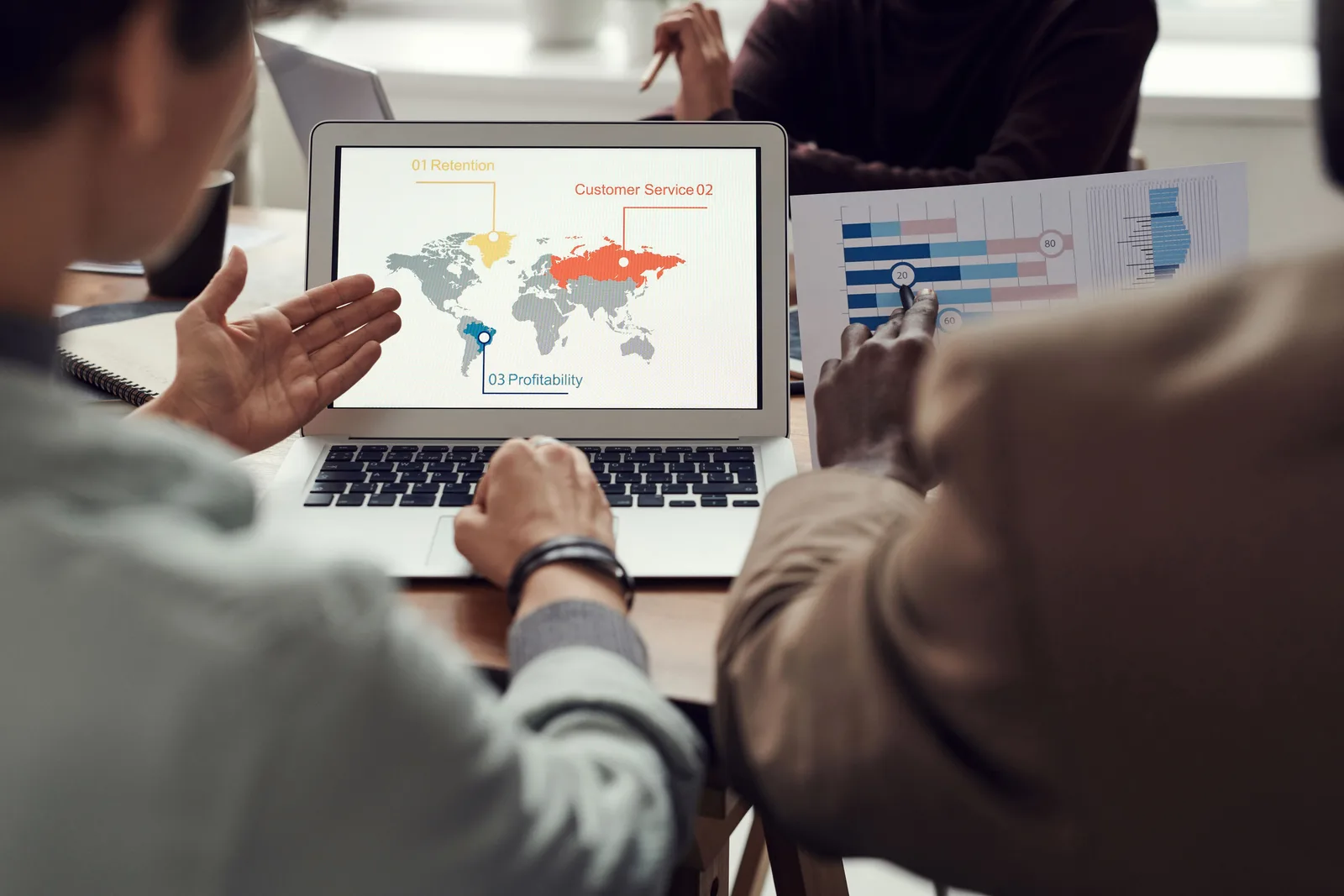 Team collaborating on business strategy with laptop displaying global analytics. Multi-location marketing tools to compare in 2027