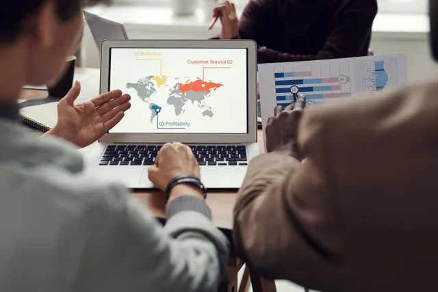 Team collaborating on business strategy with laptop displaying global analytics. Multi-location marketing tools to compare in 2027
